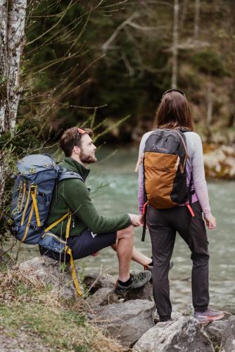 two people with backpacks standing on rocks next to a river at Hotel-Gasthof Der Wiesengrund in Bad Hindelang
