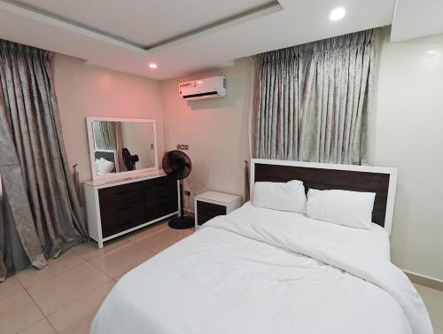 a bedroom with a large white bed and a mirror at Awka Modern Apartment in Awka