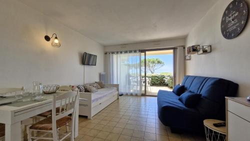 a living room with a blue couch and a table at Saint Georges de Didonne - VUE MER pour ce STUDIO COSY en rez-de-chaussée in Saint-Georges-de-Didonne