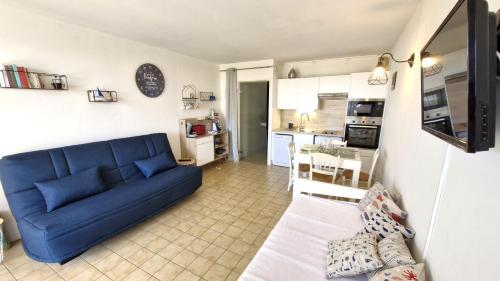 un salon avec un canapé bleu et une cuisine dans l'établissement Saint Georges de Didonne - VUE MER pour ce STUDIO COSY en rez-de-chaussée, à Saint-Georges-de-Didonne