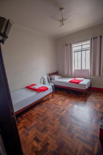 two beds in a room with a wooden floor at Hotel Pousada Zacarias in Anápolis