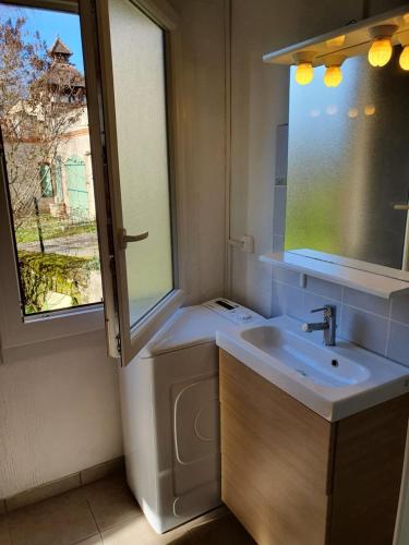 une salle de bain avec un lavabo et une fenêtre dans l'établissement La Maison au Tilleul, à Labarthe-Bleys