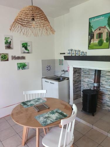 - une cuisine avec une table en bois et des chaises blanches dans l'établissement La Maison au Tilleul, à Labarthe-Bleys