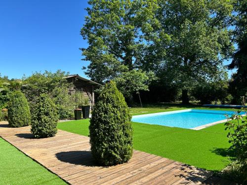 a garden with a swimming pool and some bushes at Maison de vacances Bazas in Lignan-de-Bazas