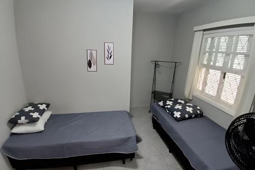 a bedroom with two beds and a window at Estilo e Conforto no Gonzaga – Uma Joia em Santos! in Santos