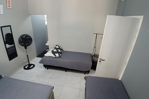 a room with a couch and a chair and a fan at Estilo e Conforto no Gonzaga – Uma Joia em Santos! in Santos
