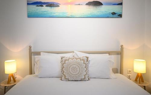 a bedroom with a white bed with two lamps at Jenny Sam renovated house for 5 near center and be in Skiathos Town