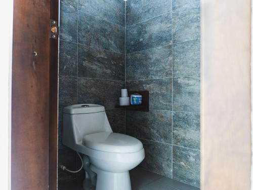 a bathroom with a toilet and a tiled wall at Huku Beach Hostel in Palomino