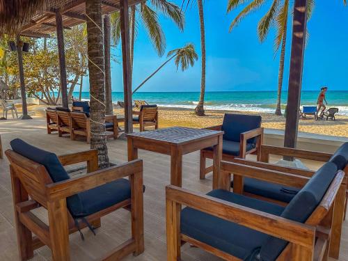 a beach with chairs and tables and the ocean at Huku Beach Hostel in Palomino