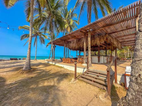 a hut on the beach with palm trees at Huku Beach Hostel in Palomino