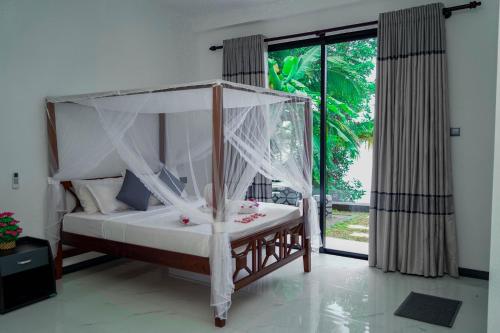 a bedroom with a canopy bed and a large window at Elegance Lake View in Habaraduwa Central