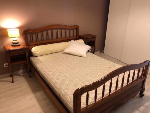 - une chambre avec un lit en bois et 2 tables de chevet dans l'établissement Maison 2 chambres et 2 lits simple Jardin en centre ville, à Carcans