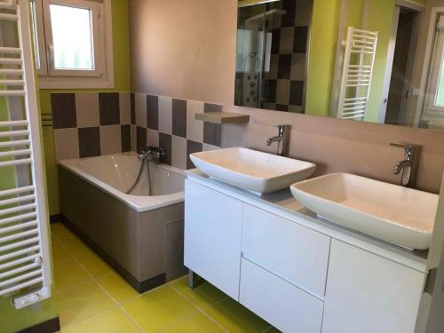 une salle de bain avec deux lavabos et une baignoire dans l'établissement Maison 2 chambres et 2 lits simple Jardin en centre ville, à Carcans