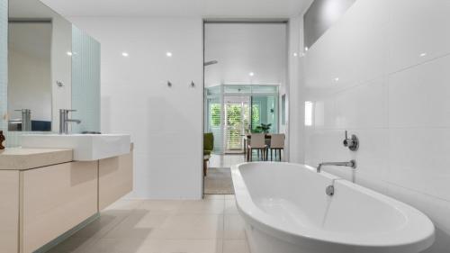 a white bathroom with a tub and a sink at Bayside at 201 Lake Street in Cairns North
