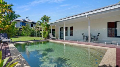 a swimming pool in front of a house at Poolside Palms Villa in Trinity Beach