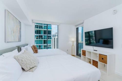 a white bedroom with a large bed and a tv at Exclusive, Amazing, Bright and Spacious at Brickell in Miami