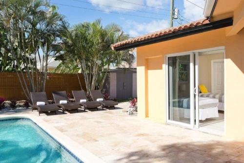 a patio with a pool and chairs next to a house at Beautiful Villa 4 BD 3 BA with Heated Private Pool, Close to Beach in Boca Raton