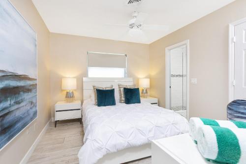 a bedroom with a white bed with blue pillows at Beautiful Villa 4 BD 3 BA with Heated Private Pool, Close to Beach in Boca Raton