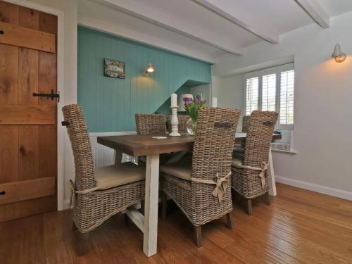 comedor con mesa de madera y sillas de mimbre en Trelan, en St Austell
