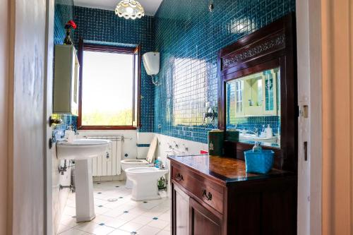 a blue tiled bathroom with a sink and a toilet at Villa Pina in Priverno