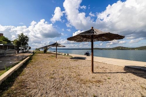 a beach with two umbrellas on the side of the water at Sydney Apartment in Bilice