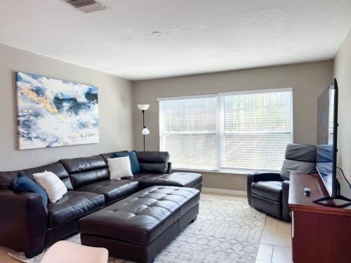 a living room with a leather couch and a television at Entire Home in Dade City! in Dade City