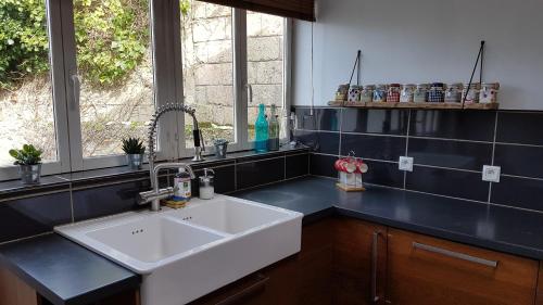une cuisine avec un évier blanc et une fenêtre dans l'établissement Camaret maison grand jardin, à Camaret-sur-Mer