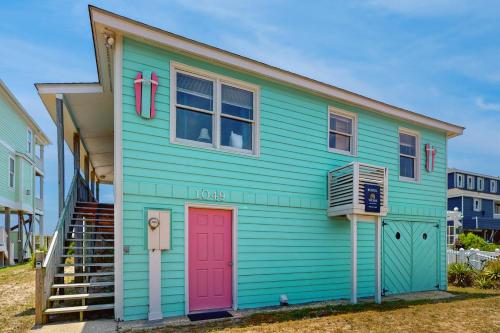 a blue and green house with a red door at Beachy Keen in Holden Beach