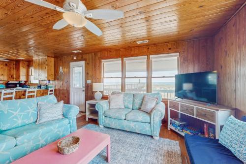 a living room with blue furniture and a flat screen tv at Beachy Keen in Holden Beach