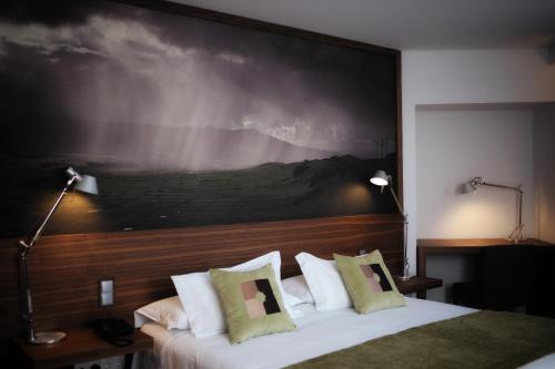 a bedroom with a large painting above a bed at Hotel Cruzeiro in Angra do Heroísmo