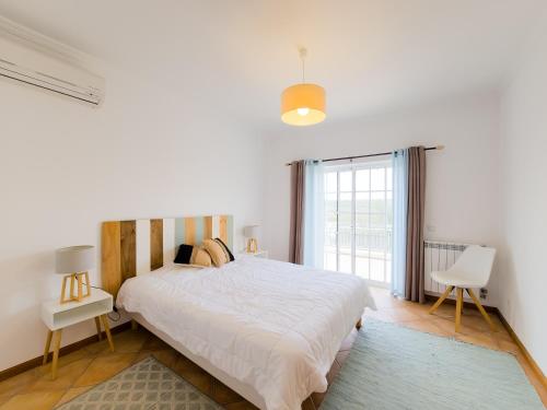 a white bedroom with a large bed and a window at Casa Marina V4 by YHA in Tavira