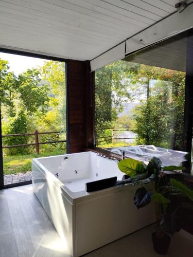 a bath tub in a room with a large window at Dobau casas in Vieira do Minho
