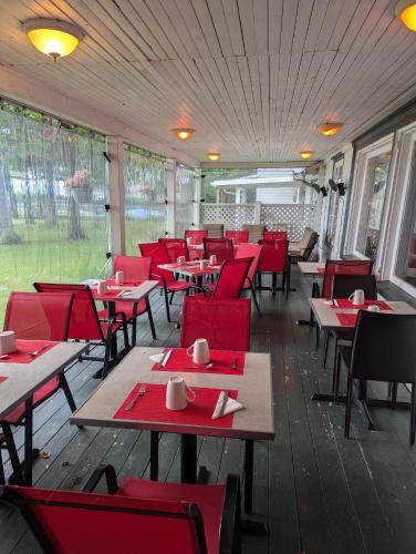 a dining room with red chairs and tables in a restaurant at Auberge Les Blancs Moutons in Saint-Laurent-de-l'ile d'Orleans