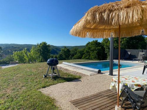 un grill et un parasol en paille à côté d'une piscine dans l'établissement Vacances Vallée de la Dordogne, à Souillac
