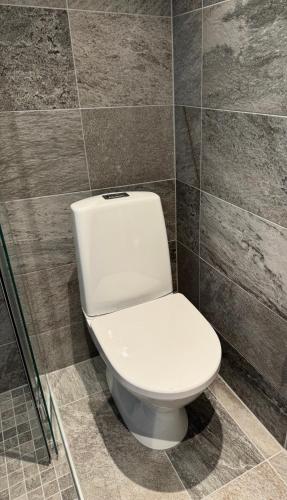 a white toilet in a bathroom with a tile wall at Toftemo Turiststasjon in Dovre