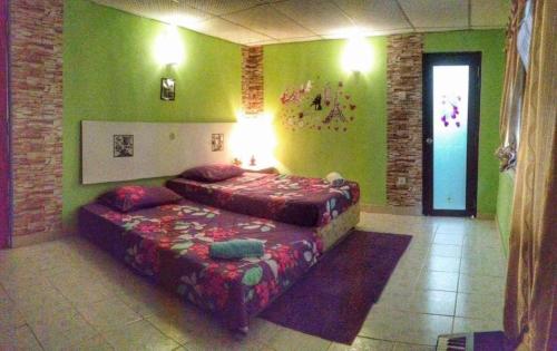 a bedroom with two beds in a room with green walls at sleepy hollow guesthouse in Pantai Cenang