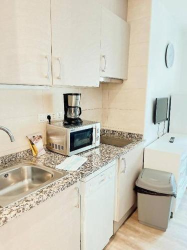 a small kitchen with a sink and a microwave at Sky 503 by CONFORTSKY in Pas de la Casa