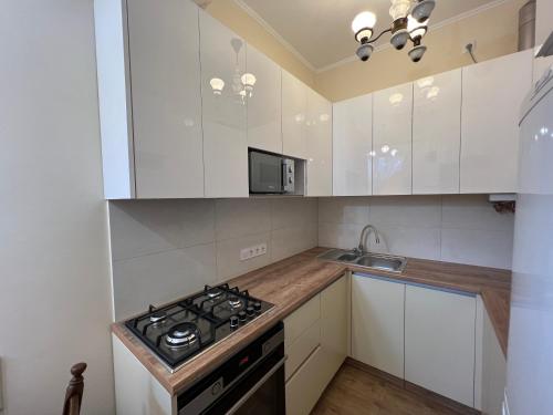 a kitchen with white cabinets and a stove top oven at Dominican in Lviv