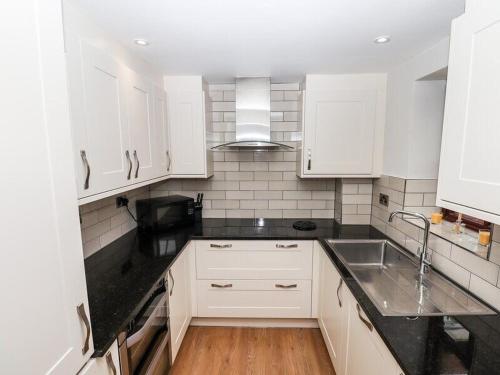 Una cocina con gabinetes blancos y un fregadero. en Luxury Penthouse on Waterside Knaresborough, en Knaresborough