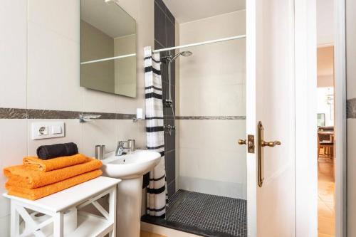 a bathroom with a sink and a shower with orange towels at Villa Sidanya by Villa Plus in Cala en Porter