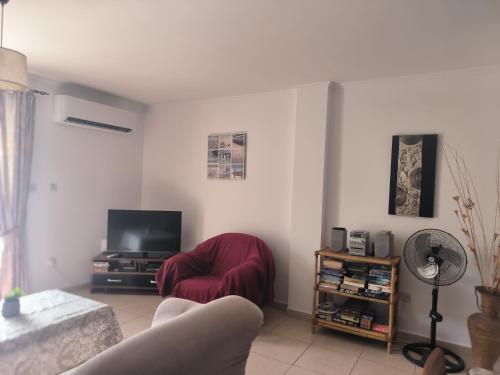 a living room with a red chair and a television at 3 Bedroom Affordable Apartment in Oroklini with Communal Pool in Voroklini