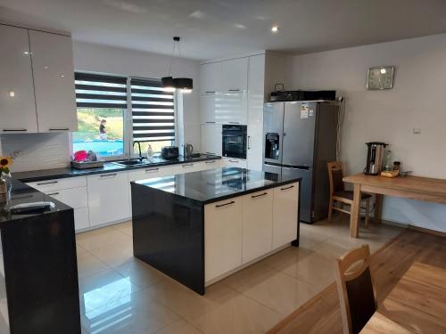 a large kitchen with white cabinets and black appliances at Leśna Skałka in Bobolice