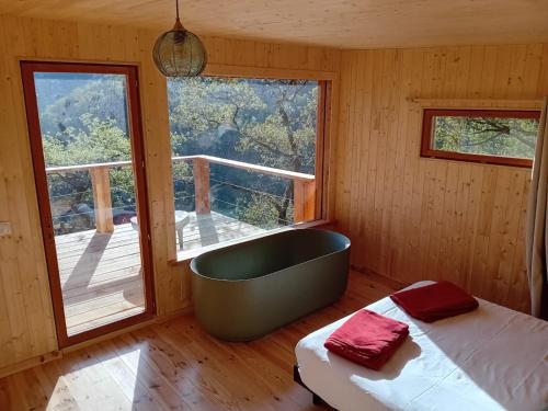 a bedroom with a tub and a bed and a window at Hêtre sous le Charme in Saint-Martial-Entraygues
