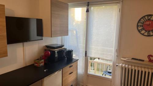 una cucina con bancone e finestra con orologio di apart 94160 studio a Saint-Mandé