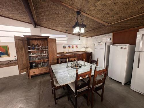 a kitchen with a table and a white refrigerator at Pousada Cantinho de Minas Da Tânia in Cabo Frio