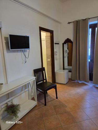 sala de estar con silla y TV en la pared en Nostra casa rooms, en Palermo