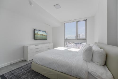 a white bedroom with a bed and a window at Stylish Stay in the Heart of Miami - Walk to Bayside & Bayfront Park in Miami