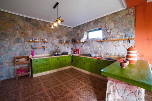 a kitchen with green cabinets and a stone wall at MesklilHouse in Asilah