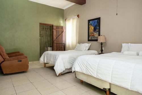 a bedroom with two beds and a chair and a window at Hokhmah Heart Hotel in Puerto Morelos