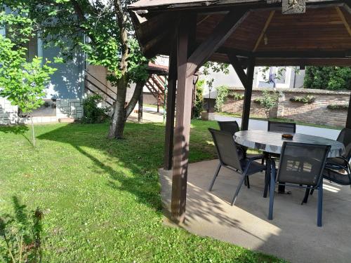a table and chairs under a gazebo in a yard at Apartman kod dide i bake in Vukovar